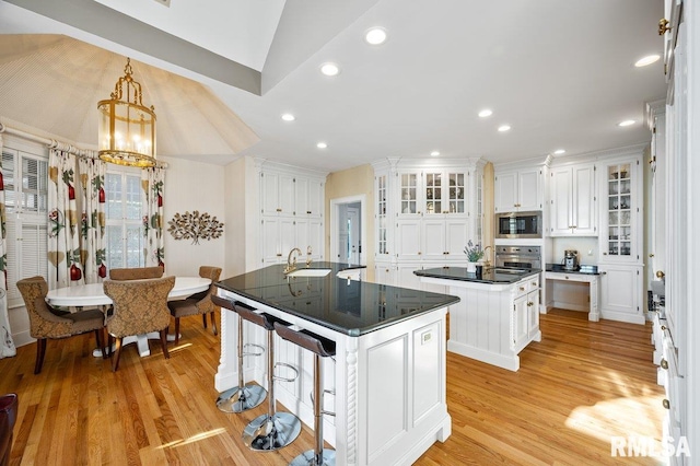 kitchen with sink, hanging light fixtures, appliances with stainless steel finishes, a kitchen island, and white cabinetry