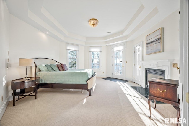 carpeted bedroom featuring a tray ceiling and access to outside