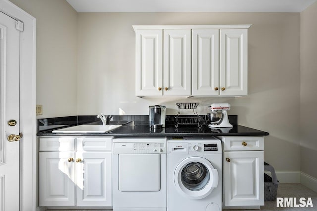 clothes washing area featuring cabinets, washer and clothes dryer, and sink