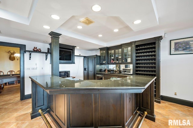 kitchen with a raised ceiling, dark brown cabinets, and a spacious island