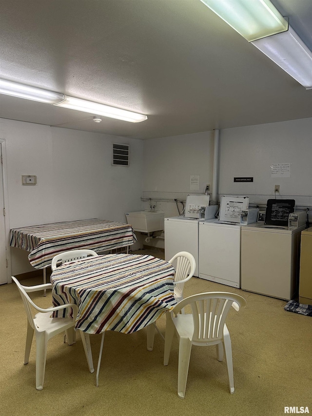 washroom featuring washing machine and dryer, light carpet, and sink