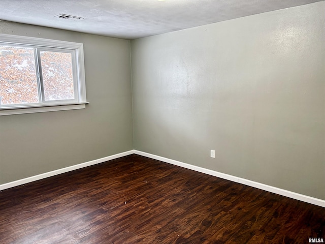 empty room with dark hardwood / wood-style flooring and a textured ceiling