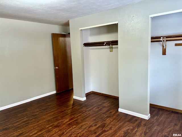 unfurnished bedroom featuring a textured ceiling, a closet, and dark wood-type flooring