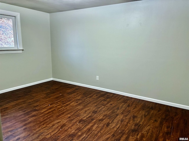 spare room featuring dark wood-type flooring and baseboards