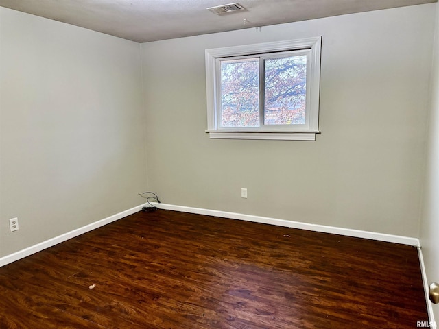 empty room featuring visible vents, baseboards, and wood finished floors