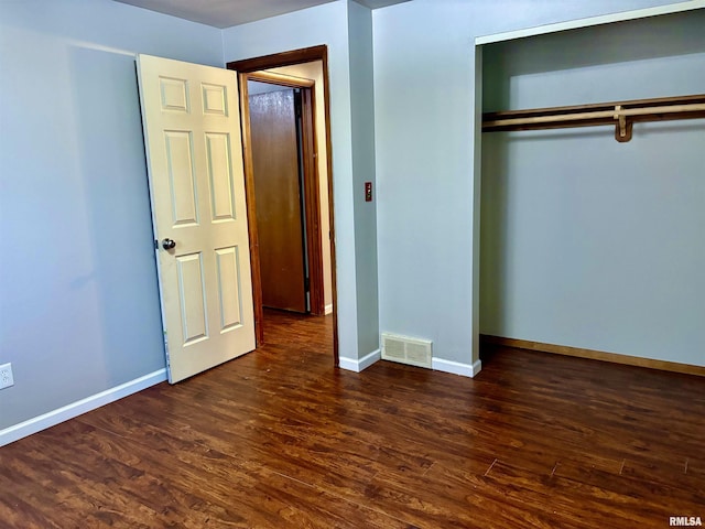 unfurnished bedroom with a closet, dark wood-style flooring, visible vents, and baseboards