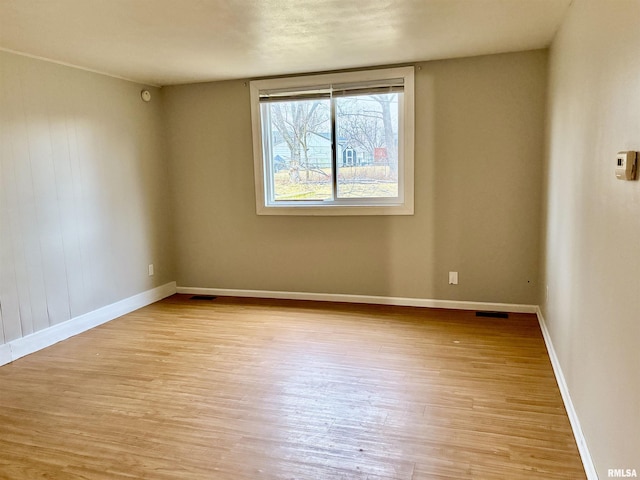 spare room featuring light wood-style floors, visible vents, and baseboards