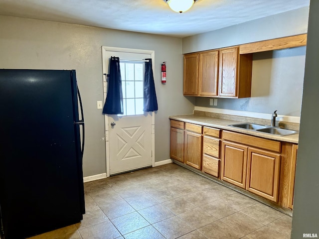 kitchen featuring light tile patterned flooring, black fridge, and sink