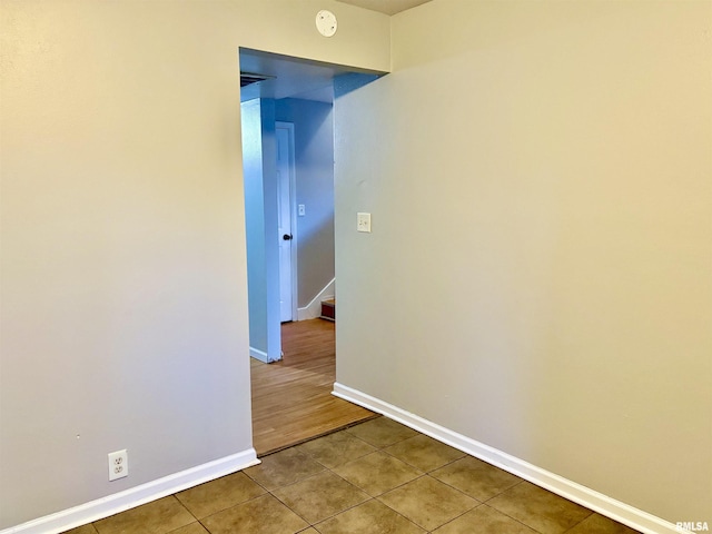 tiled spare room featuring baseboards and stairs