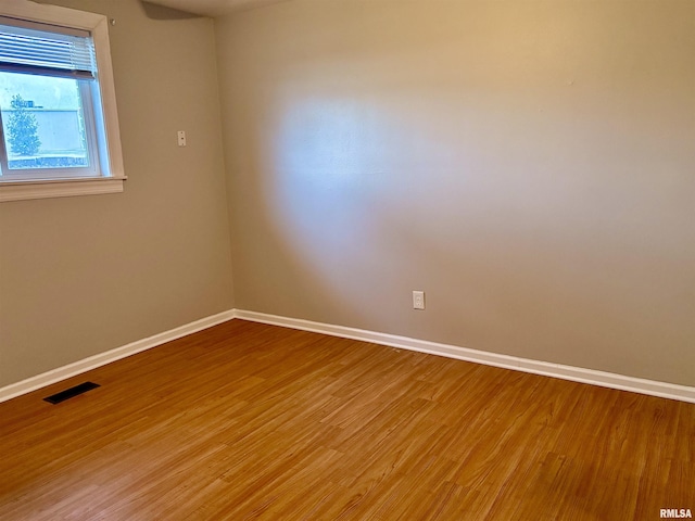 unfurnished room featuring visible vents, baseboards, and wood finished floors