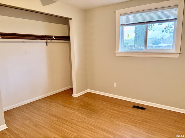 unfurnished bedroom with baseboards, visible vents, a closet, and wood finished floors