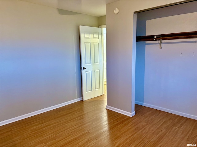 unfurnished bedroom featuring a closet, light wood-style flooring, and baseboards