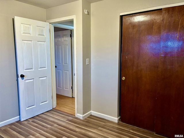 unfurnished bedroom with a closet, wood finished floors, and baseboards