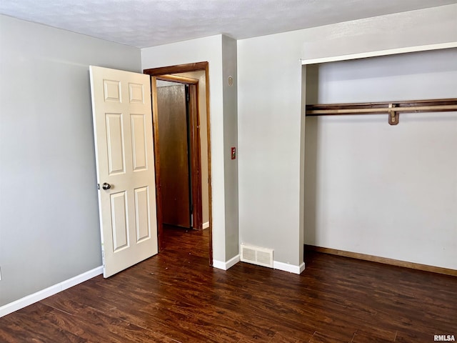 unfurnished bedroom with a textured ceiling, a closet, and dark hardwood / wood-style floors