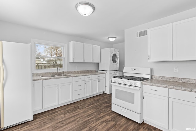 kitchen with white cabinets, white appliances, stacked washer / drying machine, and sink