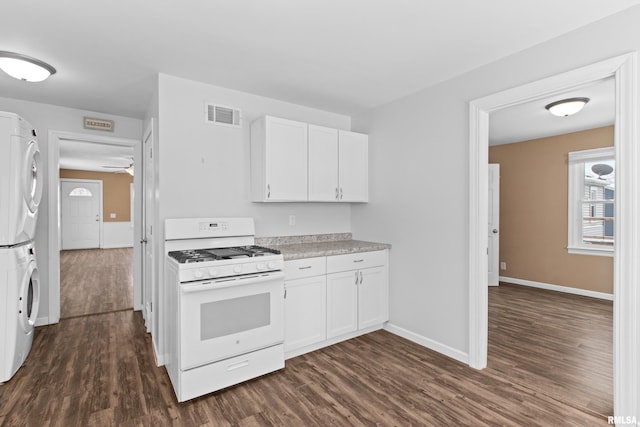 kitchen featuring white cabinetry, gas range gas stove, dark wood-type flooring, and stacked washing maching and dryer