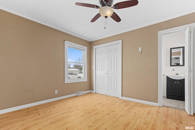 unfurnished bedroom with ceiling fan, light hardwood / wood-style floors, ensuite bathroom, and a closet