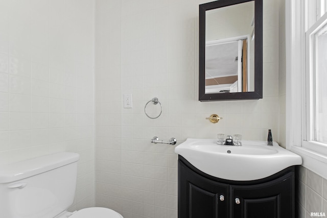 bathroom with vanity, toilet, and tile walls