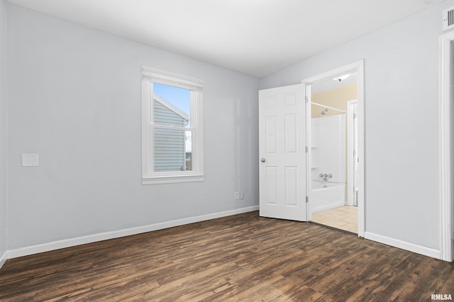 unfurnished bedroom featuring connected bathroom and dark hardwood / wood-style floors