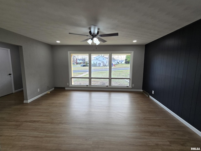 spare room featuring hardwood / wood-style flooring, ceiling fan, and wooden walls