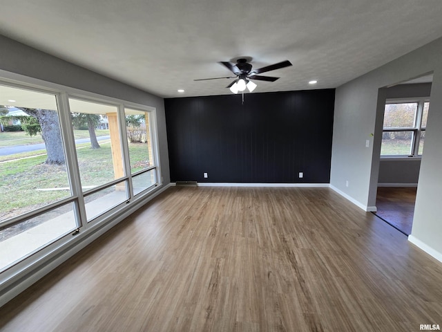 spare room with a wealth of natural light, ceiling fan, and wood-type flooring