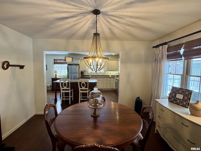 dining space featuring a healthy amount of sunlight, dark hardwood / wood-style flooring, sink, and a chandelier