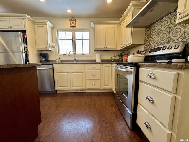 kitchen with dark hardwood / wood-style floors, sink, stainless steel appliances, and wall chimney range hood