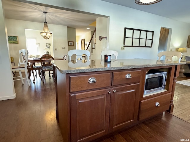 kitchen with a kitchen island, hanging light fixtures, dark hardwood / wood-style floors, and a notable chandelier