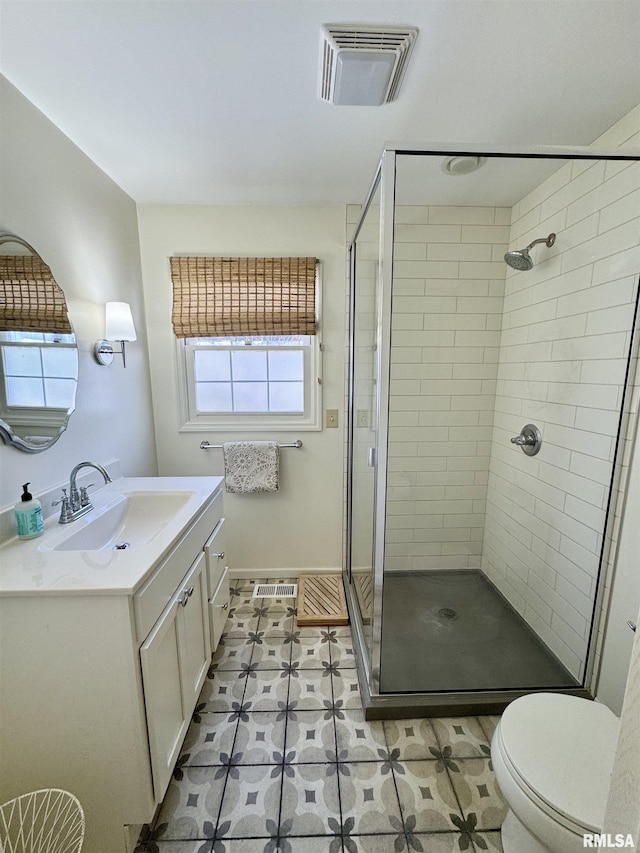 bathroom featuring vanity, a shower with shower door, and toilet