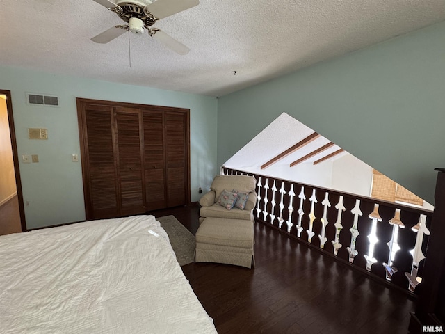 bedroom with ceiling fan, dark hardwood / wood-style floors, a textured ceiling, and a closet