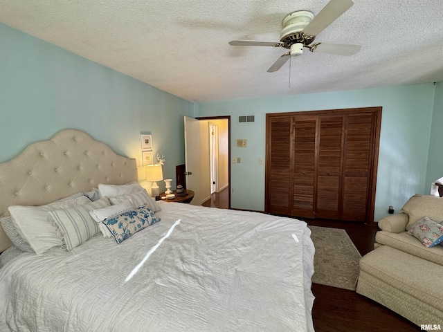 bedroom featuring ceiling fan, dark hardwood / wood-style flooring, and a textured ceiling