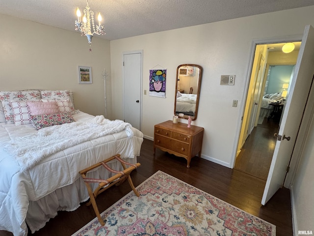 bedroom featuring dark wood-type flooring, a textured ceiling, and a notable chandelier