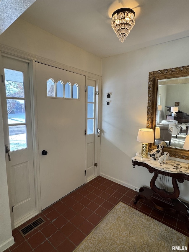 tiled foyer entrance featuring an inviting chandelier