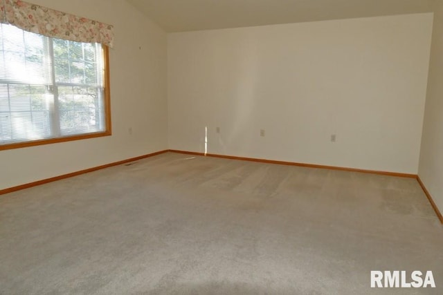 carpeted empty room featuring vaulted ceiling