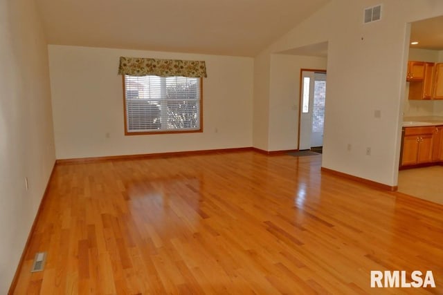 empty room with light hardwood / wood-style floors and vaulted ceiling