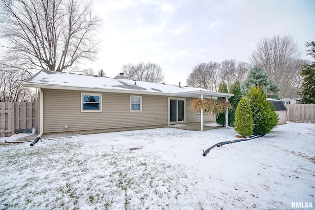 snow covered back of property with a storage shed