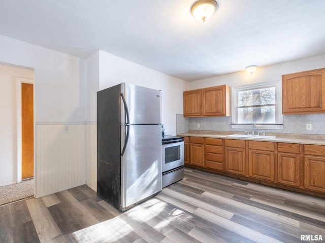 kitchen with tasteful backsplash, sink, light hardwood / wood-style flooring, and appliances with stainless steel finishes