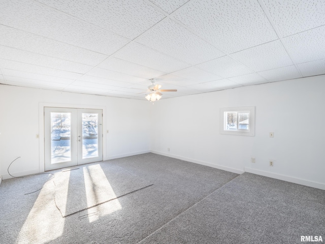 empty room with dark colored carpet, a drop ceiling, ceiling fan, and french doors