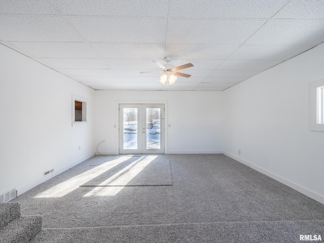 empty room featuring a paneled ceiling, ceiling fan, carpet, and french doors