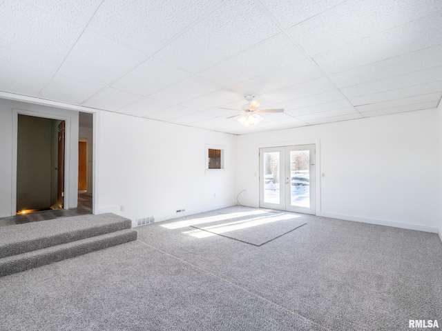 carpeted empty room featuring a drop ceiling, ceiling fan, and french doors