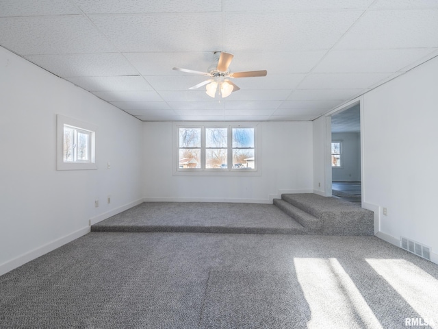 spare room featuring a wealth of natural light, a drop ceiling, carpet floors, and ceiling fan