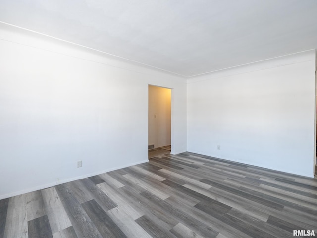 empty room featuring crown molding and dark wood-type flooring