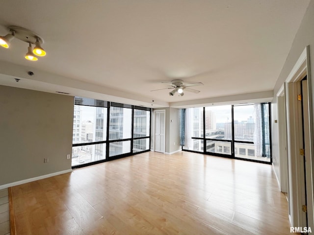 spare room featuring ceiling fan, light hardwood / wood-style floors, and expansive windows