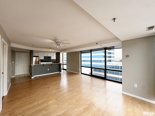 unfurnished living room featuring ceiling fan and light hardwood / wood-style flooring