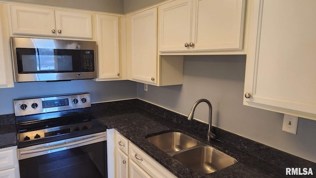 kitchen featuring dark stone counters, sink, white cabinets, and stainless steel appliances