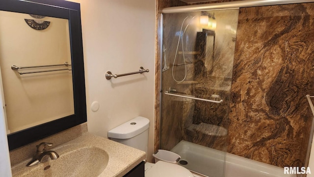 bathroom featuring an enclosed shower, vanity, and toilet