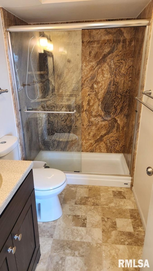 bathroom with a shower with door, vanity, and toilet