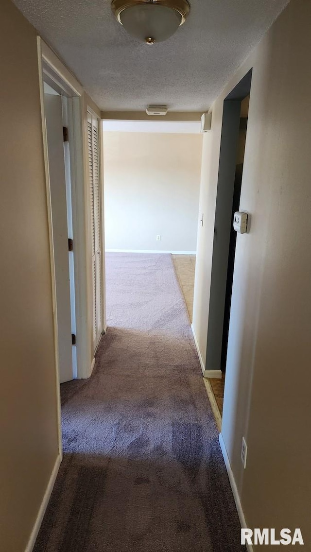 corridor featuring a textured ceiling and carpet floors