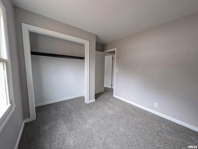 unfurnished bedroom with dark colored carpet and a closet