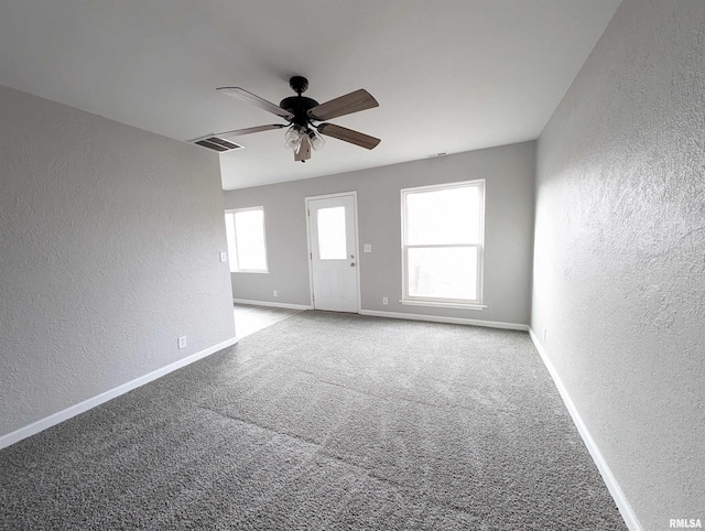 unfurnished room with plenty of natural light, carpet floors, and ceiling fan